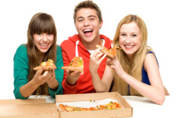 Gutt og to jenter som spiser pizza.